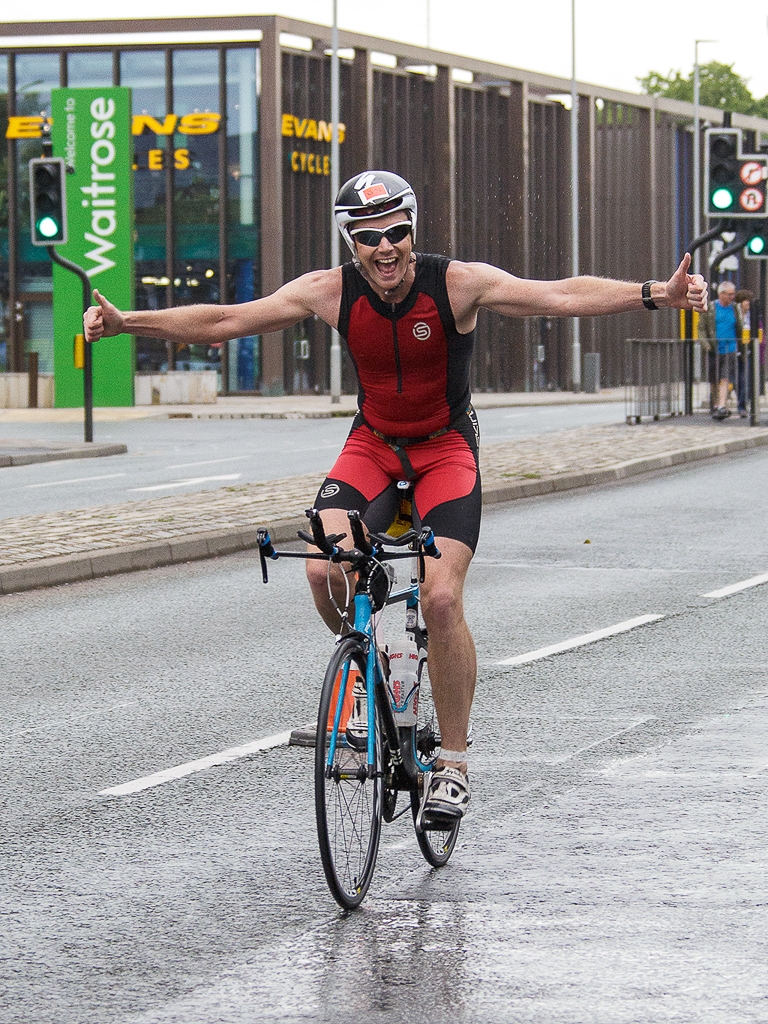 Triathlon cycling man arms outstretched in rain